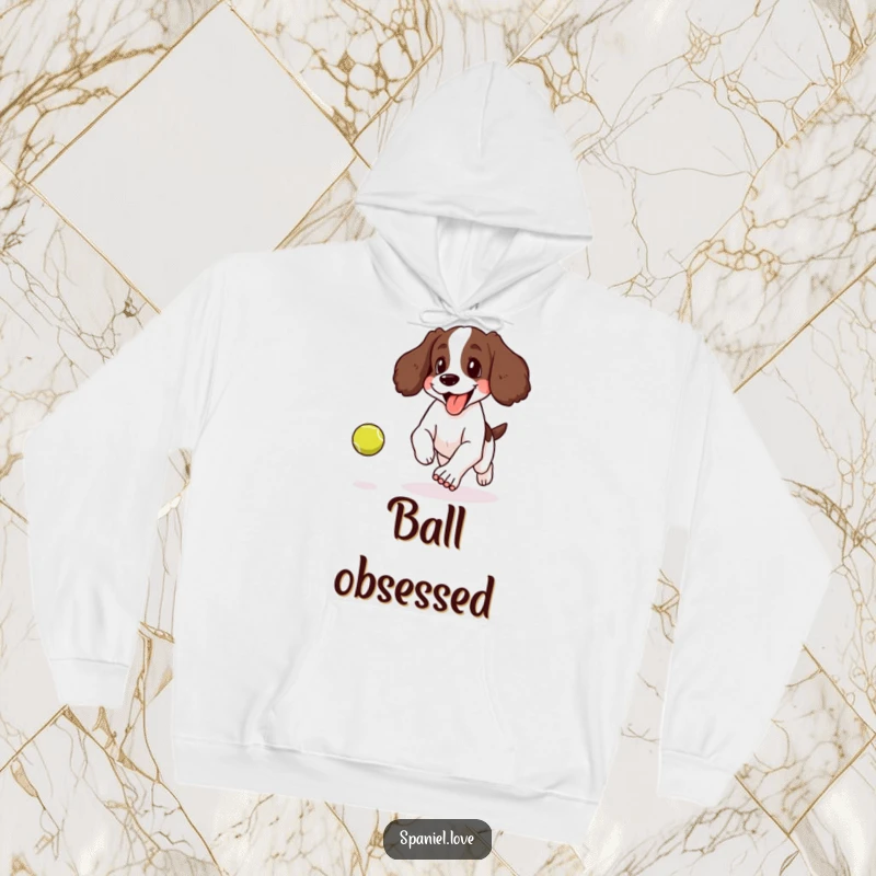Funny hoodie illustrating a spaniel joyfully panting with its tongue lolling out while chasing a bouncing tennis ball.
