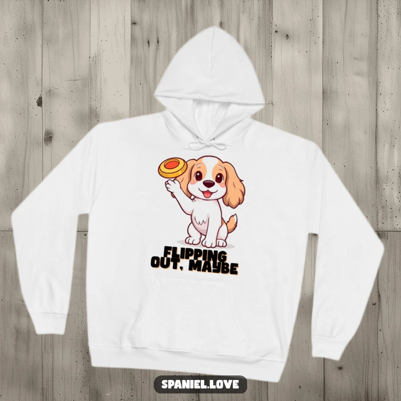 Funny Spaniel dog with one paw raised, balancing a tiny, spinning frisbee on its nose on a hoodie, offering warmth and humor.