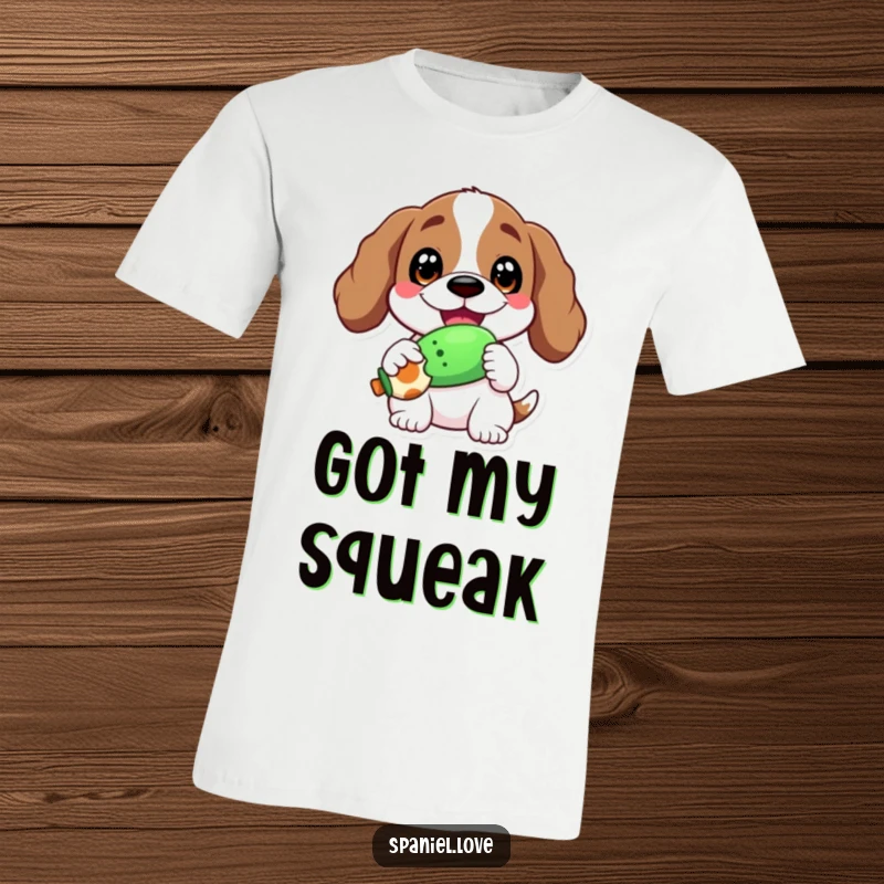 Funny t-shirt showcasing a spaniel with a wide, joyful grin, clutching a squeaky toy, radiating happiness.
