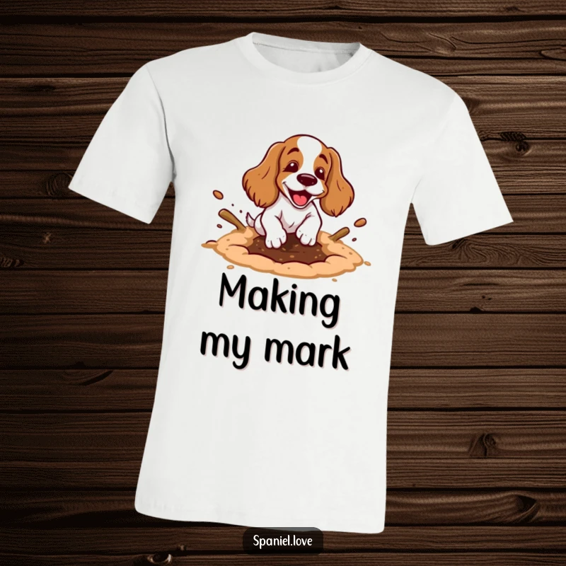 Funny spaniel t-shirt showing a cartoon spaniel happily digging a hole with exaggerated motion and dirt flying, celebrating outdoor play.